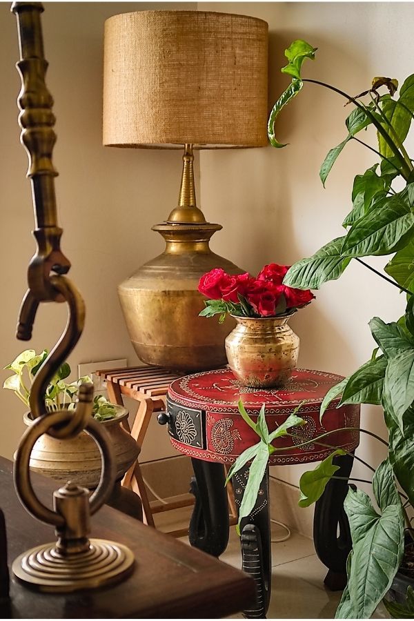 Traditional brass pot with red roses on a carved stool